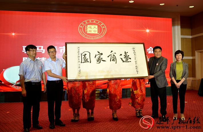 图为:遂平县人民政府副县长王红新代表遂平县委、县政府向驻马店市遂平商会赠送《遂商家园》书法牌匾。