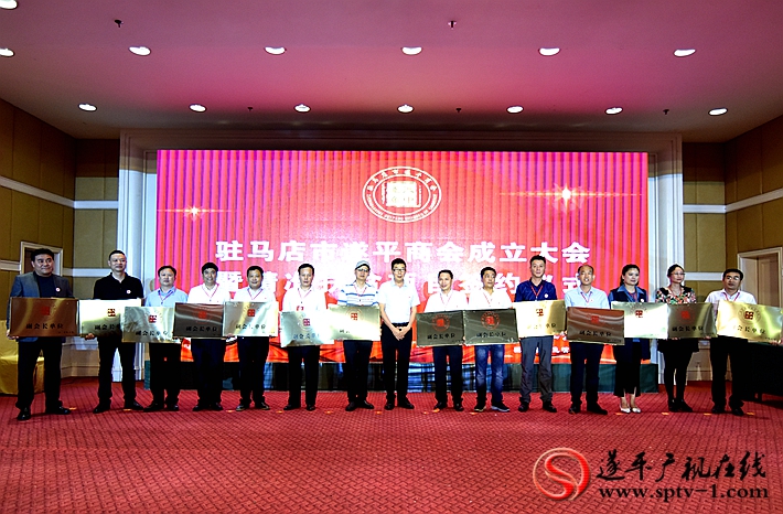 图为:遂平县人民政府副县长王红新代表遂平县委、县政府向驻马店市遂平商会赠送《遂商家园》书法牌匾