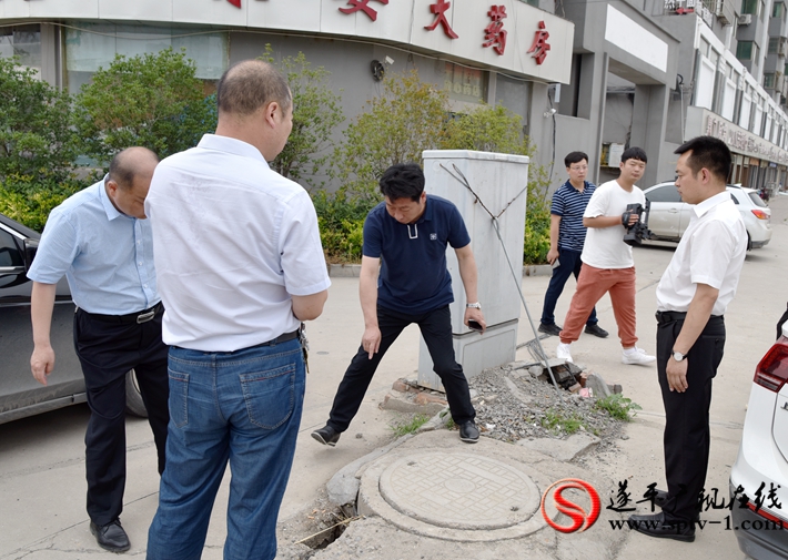 上图:县委副书记尹永彪与相关部门负责人在城南建材市场西南角查看电缆井,研究解决办法。