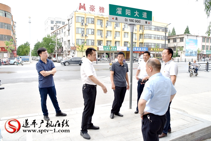 上图:县委副书记尹永彪与相关部门负责人在水果市场东南角查看人行道的铺设情况。